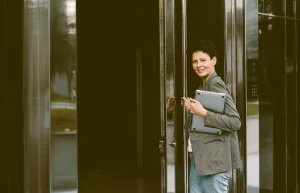 a woman entering a building with a laptop containing BS EN 16500 information on